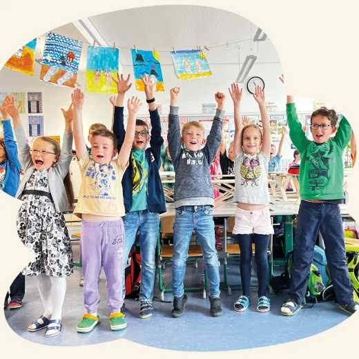Jubelnde Kinder im Klassenzimmer an Stehtischen
